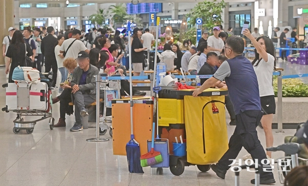 인천공항 제 1여객터미널에서 한 환경미화노동자가 청소도구를 실은 카트를 밀며 이용객들 사이로 이동하는 모습. /경인일보DB